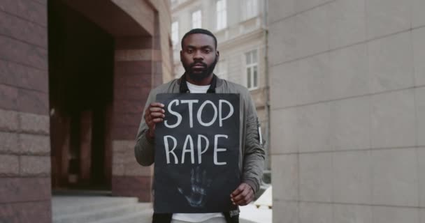 Африканського американця, який тримає картонну картку з припиненням зґвалтування, пишучи на вулицях міста. Чоловіки протестують проти насильства і нападу. Концепція соціальних проблем. Збільшити. — стокове відео