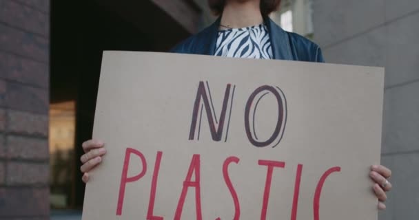 Mladá stylová dívka držící kartonový plakát bez plastového nápisu. Millennial krásná žena podporující ekologické hnutí, zatímco stojí na ulici města. Koncepce ekologického povědomí. — Stock video