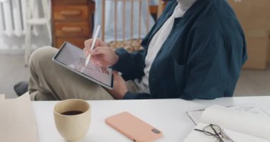 Erkek web tasarımcısı, dizlerine dijital tablet sergilenirken resim çiziyor. İş yerinde otururken Stylus 'un çizimlerini not defterine odaklan..