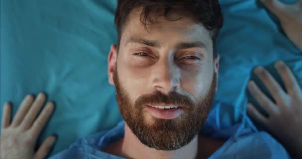 Крупный план бородатого парня, улыбающегося, лежа на больничных носилках. Парамедики проверяют пульс 40-летнему мужчине с травмами на пути в операционную. Концепция здравоохранения. — стоковое видео