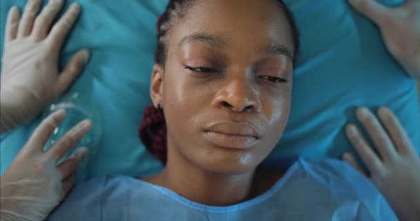 Zdravotníci kontrolují puls a nasazují dívčí obličej kyslíkovou maskou. Detailní záběr afro-americké ženy ležící na nosítkách, zatímco jde na operační sál.. — Stock video