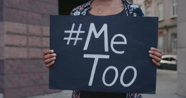 Вид на афроамериканські руки, що тримають прапор з хештегом Metoo на ньому. Жінка підтримує протест проти сексуального насильства, стоячи на вулиці. Концепція соціальної проблеми . — стокове відео
