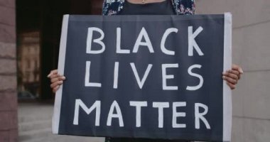 Siyahi hayatları olan afro-amerikan kadın elleri karton levha tutuyor. Sokak ortasında dururken polis şiddeti ve ırkçılığına karşı hareketi destekleyen aktivist..