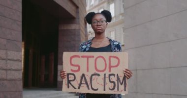 Şehir sokaklarında ırkçılık karşıtı kampanyayı destekleyen Afrikalı Amerikalı bir kız. Elinde ırkçılık terimi olan bir mukavva tutan genç bir kadın. Eşit insan hakları ve hoşgörü kavramı.