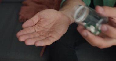 Erkeklerin eline hap alıp kanepede kurnazca oturdukları ekin manzarası. Sağlık, ilaç ve tedavi kavramı. Ellere odaklan..