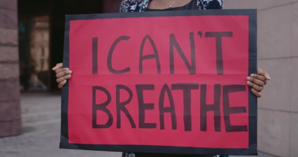 Close up of african american person holding banner with i cant breath writing on it. Female activist supporting anti racism movement while standing at street. Concept of human rights. — Stock Video