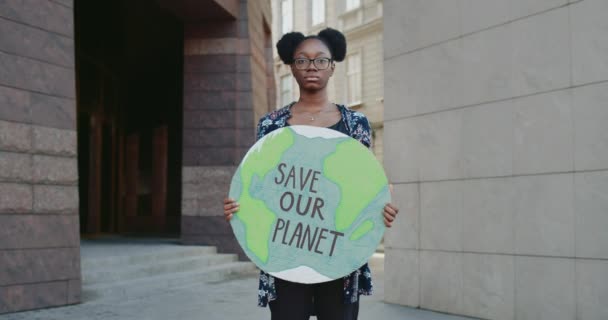 아 프로 미국 여자 애가 지구의 모델을 들고 우리의 지구 글쓰기를 저장 합니다. 심각 한 젊은 여성이 길거리 환경 오염과 싸우고 있습니다. 환경 운동의 개념이다. 줌인. — 비디오