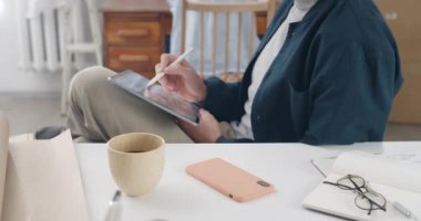 Siyah beyaz resim yaratırken grafik çizimcisinin dizinde tablet tutarken görüntüsü. Stylus 'la resim çizen bir erkek projede oturuyor ve çalışıyor. Yakınlaştır.