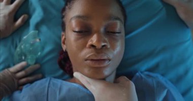 Hasta Afro-Amerikalı kızın tıbbi sedyede yatıp nabzını kontrol edişini yakından izleyin. Ambulansla hastaneye giderken ölen bir kadın. Hastalık ve sağlık sigortası kavramı.
