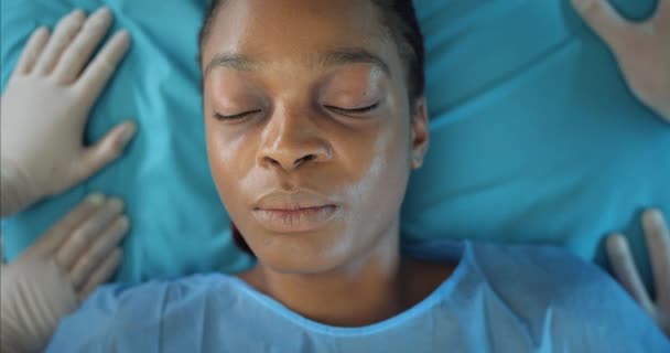 Close up of afro american girl coming to her senses while lying on hospital stretcher.Top view of young woman opening eyes in ambulance. Concept of healthcare and illness. — Stock Video