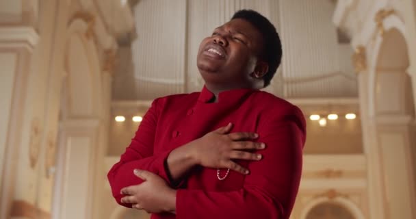 Prêcheur afro-américain chantant de la musique gospel. Jeune homme dans la trentaine portant un costume rouge jouant émotionnellement et les mains en mouvement tout en se tenant à l'église. Concept de personnes et de religion. — Video