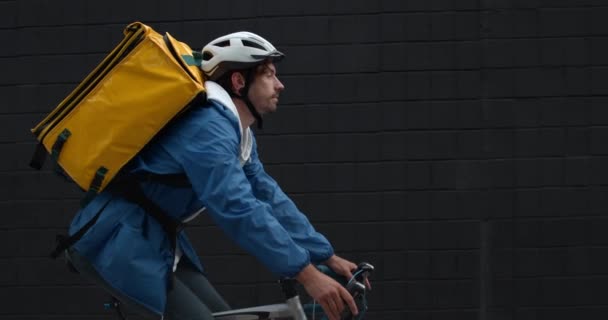 Boční pohled na mladého cyklistického kurýra s potravinovým batohem na ulici. Detailní záběr muže v ochranné přilbě doručující příkaz do úschovy. Koncepce dodávky potravin. — Stock video