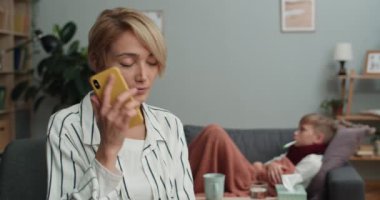 Genç kızı termometreyle kanepede yatarken güzel bir kadın arıyor ve doktorla konuşuyor. Hastalık ve sağlık sigortası kavramı.