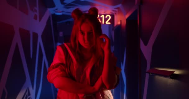 Widok na atrakcyjne kobiety pozowanie w korytarzu z futurystycznym oświetleniem neonowym. Portret zabawnej milenijnej kobiety stojącej i patrzącej w kamerę. Pojęcie ludzi. — Wideo stockowe