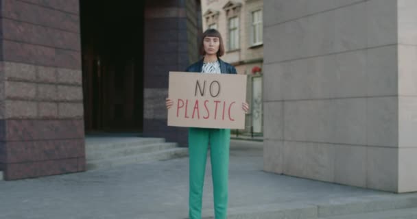 Joven mujer seria sin cartel de plástico de pie en la calle de la ciudad. Chica milenaria apoyando el movimiento de huelga de ecología. Concepto de contaminación ambiental y salvar la Tierra. Acercar. — Vídeo de stock