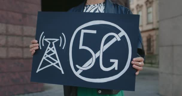 Crop view of female hands holding placard with no 5g sign. Femme faisant une seule protestation contre les nouvelles technologies et le déploiement d'antennes compatibles tout en se tenant debout dans la rue. — Video