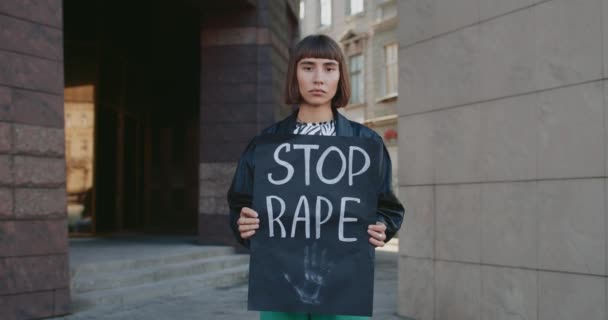 Портрет дівчини тисячоліття, що тримає прапор із стоп-зґвалтуванням, пише на міській вулиці. Жінка з кільцем для носа, що підтримує рух проти насильства та нападу. Концепція соціальних проблем . — стокове відео