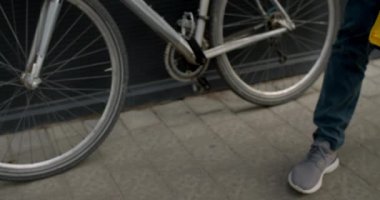Bisikletli kuryenin caddedeki ulaşım gıda paketinden kağıt paketini çıkardığı ekin manzarası. Teslimat hizmetleri kavramı.