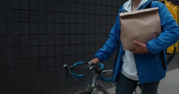 Crop kilátás férfi futár szállító karton csomag táska és tolómotor. Az utcán sétáló hátizsákkal rendelkező személy, aki a megrendelést kézbesíti az ügyfélnek. A kézbesítési szolgáltatás fogalma. — Stock videók