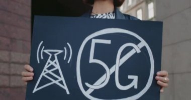 5 G işareti olmayan kadın aktivistin pankart tutmasını yakından izleyin. Hippi kadın yeni teknolojiye ve şehir caddesinde uygun anten konuşlanmasına karşı tek bir protesto yapıyor..