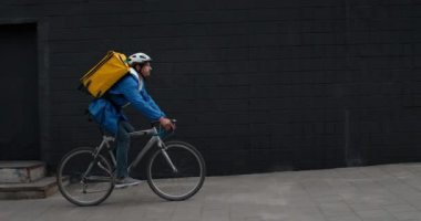 Sokakta at sırtında gezen erkek bisikletli kuryenin yan görüntüsü. Koruyucu kasklı bir adam Custumer 'a emir getiriyor. Yemek dağıtım servisi kavramı.
