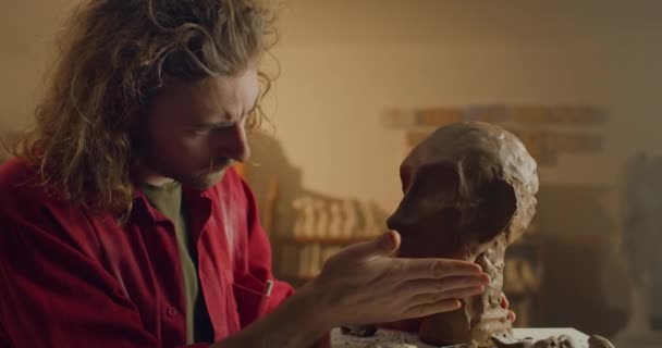 Talentueux jeune sculpteur travaillant sur la tête humaine à partir d'argile de poterie. Sérieux homme millénaire qui crée de la sculpture tout en restant debout dans un atelier d'artiste.. — Video