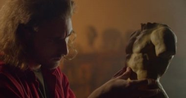 Ciddi genç heykeltıraşın alçıdan heykel gövdesi üzerinde çalışmasını yakından izleyin. Milenyum erkek heykeltıraş, sanatçının atölyesinde kil heykel yaparken detayları ayarlıyor. Sanat anlayışı..