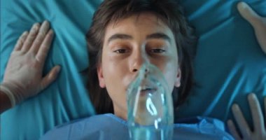 Milenyum kızı, ameliyat odasına giderken gözleri açık bir şekilde sedyede yatıyor. Ambulansa binerken hasta yüzüne oksijen maskesi takan sıhhiyecileri kapatın..