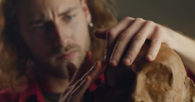 Genç sakallı adamın çömlekçilikten insan kafası şekillendirdiğine yakından bakın. Milenyum adamı sanatçı atölyesinde heykel büstü yapıyor. El yapımı sanat ve yaratıcılık kavramı..