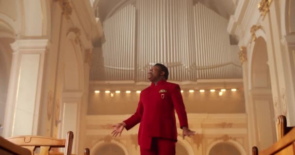 Cantante masculino emocional interpretando música de adoración. Hombre Hombre vistiendo traje rojo moviendo las manos mientras canta música espiritual en casa de oración. Concepto de religión y personas. — Vídeos de Stock