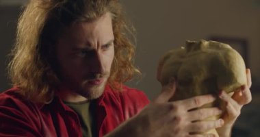 Konsantre genç erkek heykeltıraş çömlekçilikten insan gövdesi yapıyor. Ciddi milenyum adamı sanat atölyesinde heykel yapıyor. El yapımı sanat anlayışı..