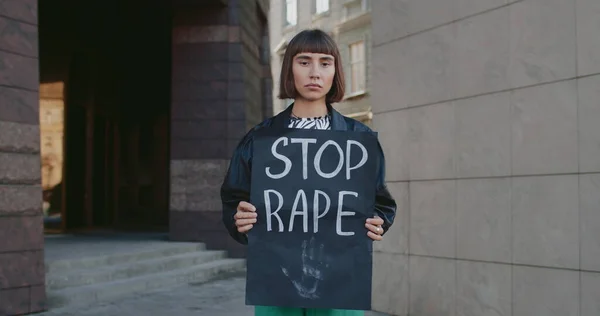 Retrato de menina milenar segurando banner com parar de estuprar escrevendo na rua da cidade. Mulher com anel nasal apoiando o movimento contra a violência e agressão. Conceito de problemas sociais. — Fotografia de Stock