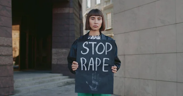 Portrait d'une jeune fille millénaire tenant une bannière avec arrêt de l'écriture de viol dans la rue de la ville. Femme avec anneau nasal soutenant le mouvement contre la violence et les agressions. Notion de problèmes sociaux. Images De Stock Libres De Droits