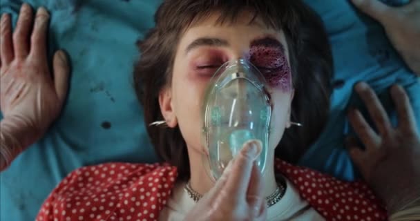 Hipster-Frau mit Verletzungen und Sauerstoffmaske liegt auf Krankenhaustrage im Krankenwagen. Nahaufnahme eines tausendjährigen Mädchens mit Blut und Wunden am Kopf Sanitäter transportieren in Klinik. — Stockvideo