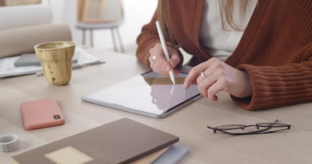 Vista da colheita de web designer feminino inovador sentado e trabalhando na mesa. Concentre-se em mãos femininas desenhando e usando caneta com tablet digital enquanto cria ilustração digital. — Vídeo de Stock