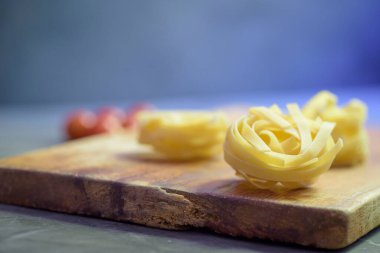 buğday unu makarna yuvası, kiraz domatesleri ve tahtanın üzerinde buğday kulağı.