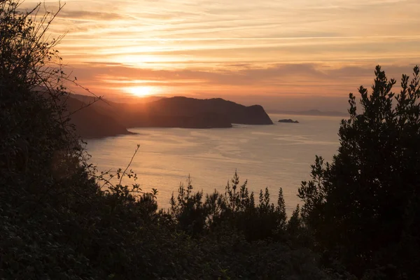 San Juan de Gaztelugatxe yakınlarındaki turuncu gökyüzü ile gün batımı Bermeo, Vizcaya, Bask Ülkesi, İspanya, Avrupa 'da bir adada yer almaktadır.