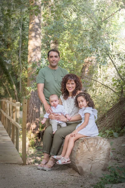 Baba, anne, bebek ve kızdan oluşan aile bir korulukta bir ağaç kütüğünde oturuyor..