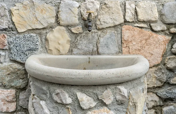 Old stone sink in front of an old stone wall