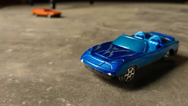 選択的に焦点を当てた車のおもちゃ 背景にオレンジ色のおもちゃの車と多様な背景の子供のための青いおもちゃの車のクローズアップ — ストック写真