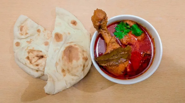 Chicken curry Masala spicy curry meat food in a white bowl with naan bread on wooden background.