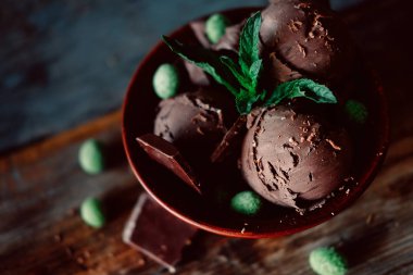 Koyu kakao dondurma üç kepçe çikolata nane yaprakları ve baharatlı kaplı yeşil fıstık ile serpilir