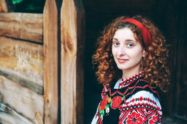 Genç Slavonic kadın geleneksel işlemeli kostüm ve verandada oturan kırmızı ayakkabılar