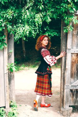 Genç Slavonic kadın geleneksel işlemeli kostüm ve verandada oturan kırmızı ayakkabılar