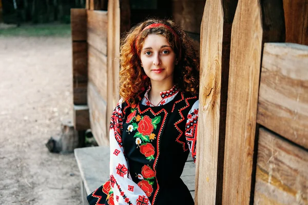 伝統的な刺繍の衣装と赤い靴の縁側に座って若いスラヴ語女性 — ストック写真
