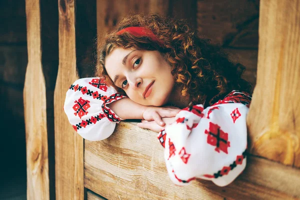 Genç Slavonic kadın geleneksel işlemeli kostüm ve verandada oturan kırmızı ayakkabılar