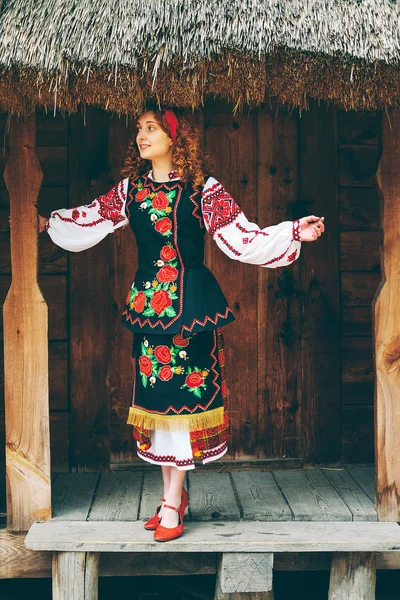Genç Slavonic kadın geleneksel işlemeli kostüm ve verandada oturan kırmızı ayakkabılar