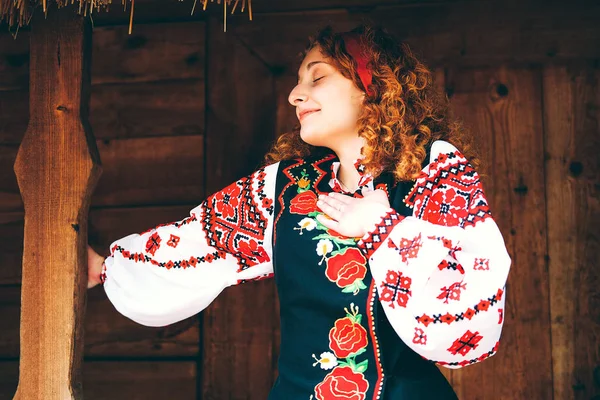 Genç Slavonic kadın geleneksel işlemeli kostüm ve verandada oturan kırmızı ayakkabılar