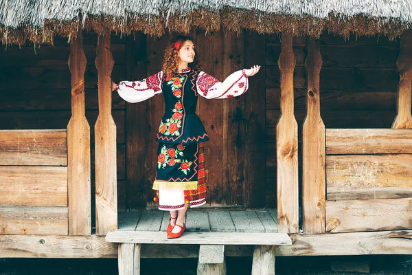 Genç Slavonic kadın geleneksel işlemeli kostüm ve verandada oturan kırmızı ayakkabılar