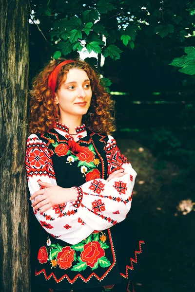 Genç Slavonic kadında geleneksel kostüm işlemeli ve kırmızı ayakkabılar ile eski ahşap kapı açma çapraz